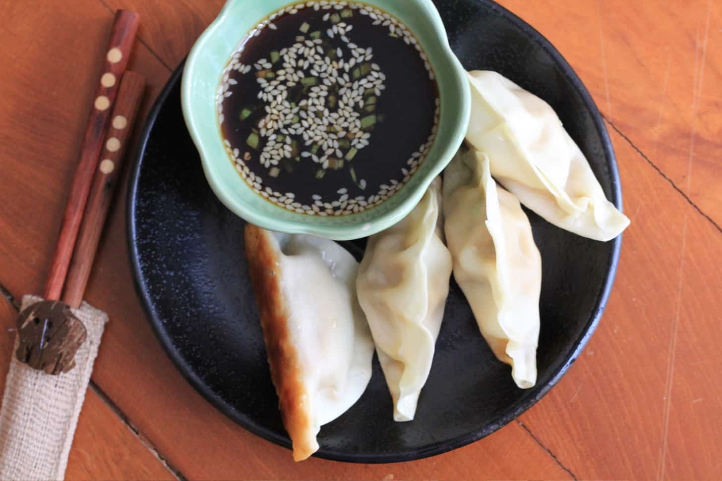 Pork Gyoza with Dipping Sauce gyoza and dipping sauce on a black plate