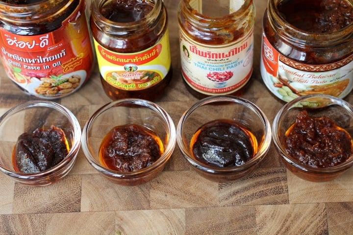 jars of Thai chili paste and bowls of chili paste on a wooden table