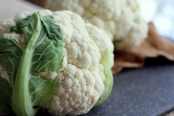 a head of raw cauliflower on a grey cutting board