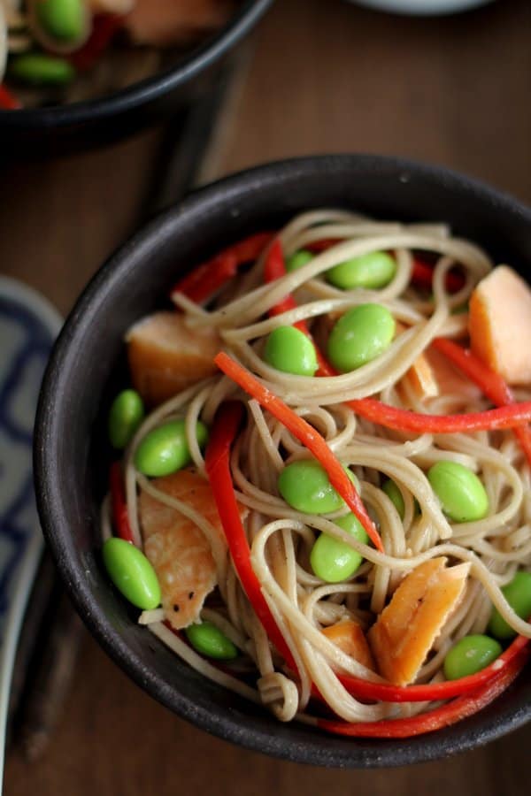 soba noodles, edamame and salmon in a black bowl