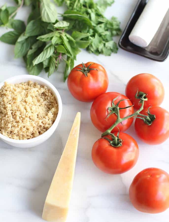tomatoes, cheese, quinoa and basil on a marble countertop