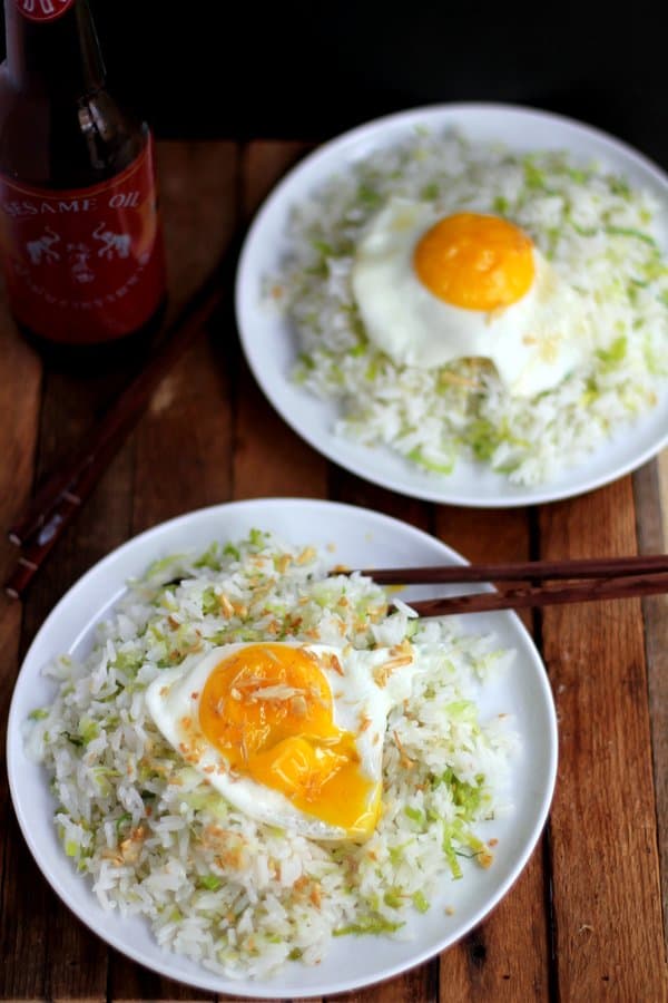 fried rice with fried eggs on white plates with chopsticks